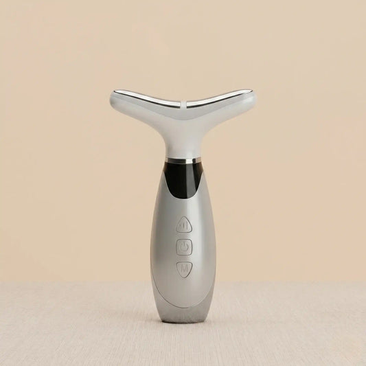 Silver facial massager on a beige background