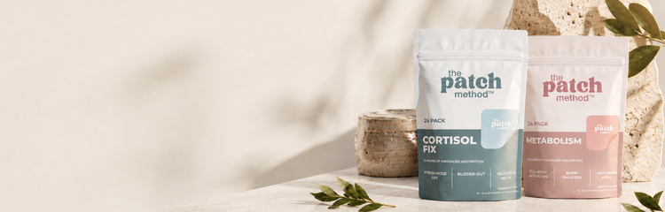 Cortisol Fix and Metabolism pouches standing side by side on a marble surface with decorative stone and greenery