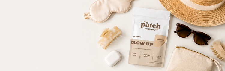 Glow Up pouch surrounded by a sun hat, sunglasses, silk eye mask, hair clip, earbuds case, and canvas pouch on a cream background