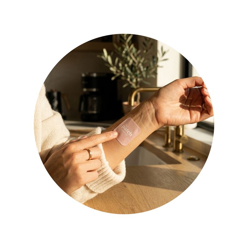 Woman applying a pink The Patch Method wellness patch to her wrist at home, representing healthy blood sugar balance support within The Lab personalized wellness plan.