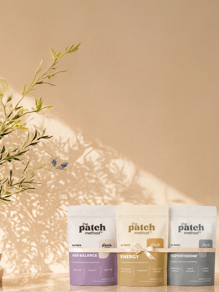 Three Patch Method pouches (Her Balance, Energy, Testosterone) standing upright on a sunlit tan surface with dried greenery