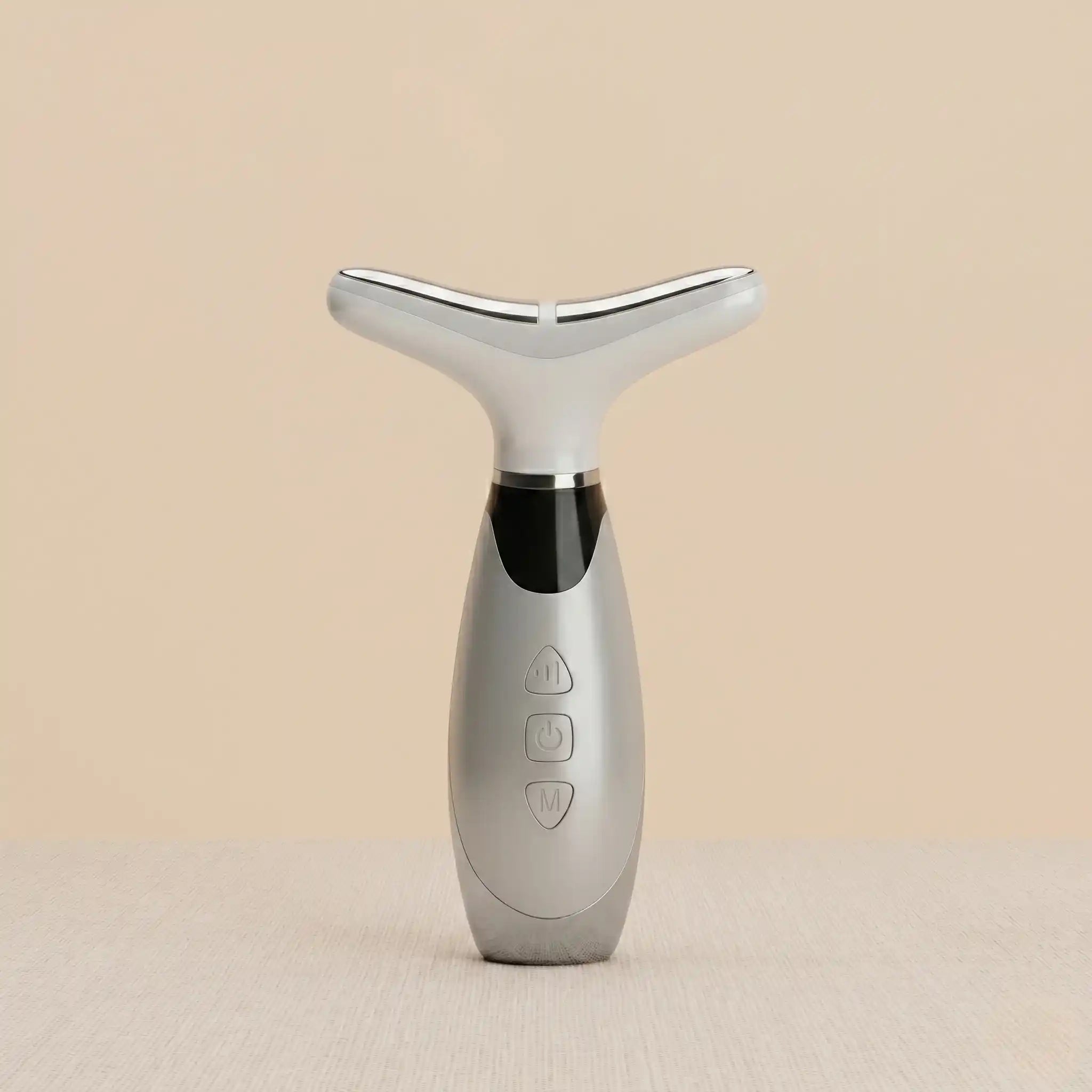 Silver facial massager on a beige background